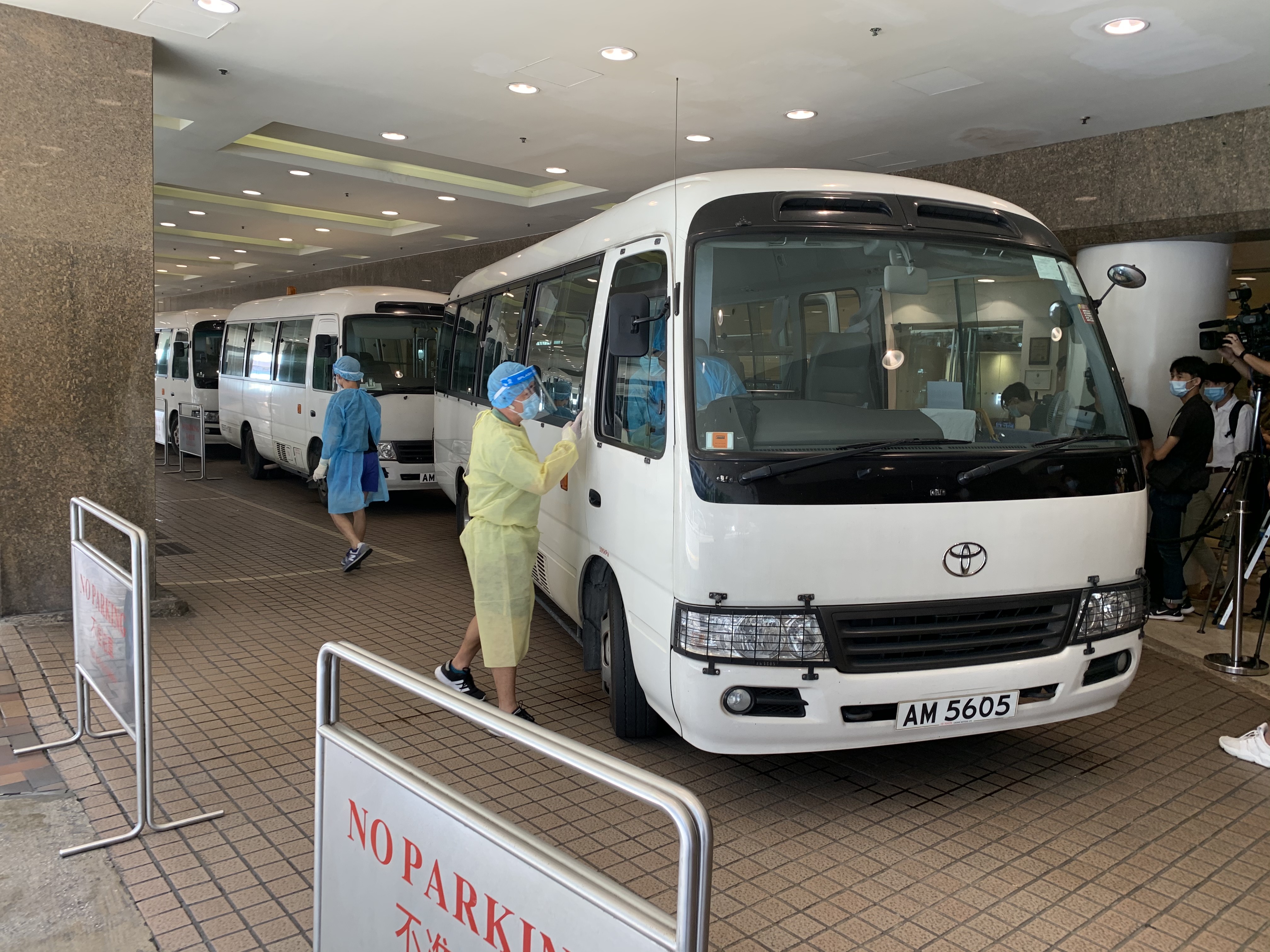 衞生署安排3輛中型旅遊巴，接載57名酒店男員工去往檢疫中心（大公報記者攝）