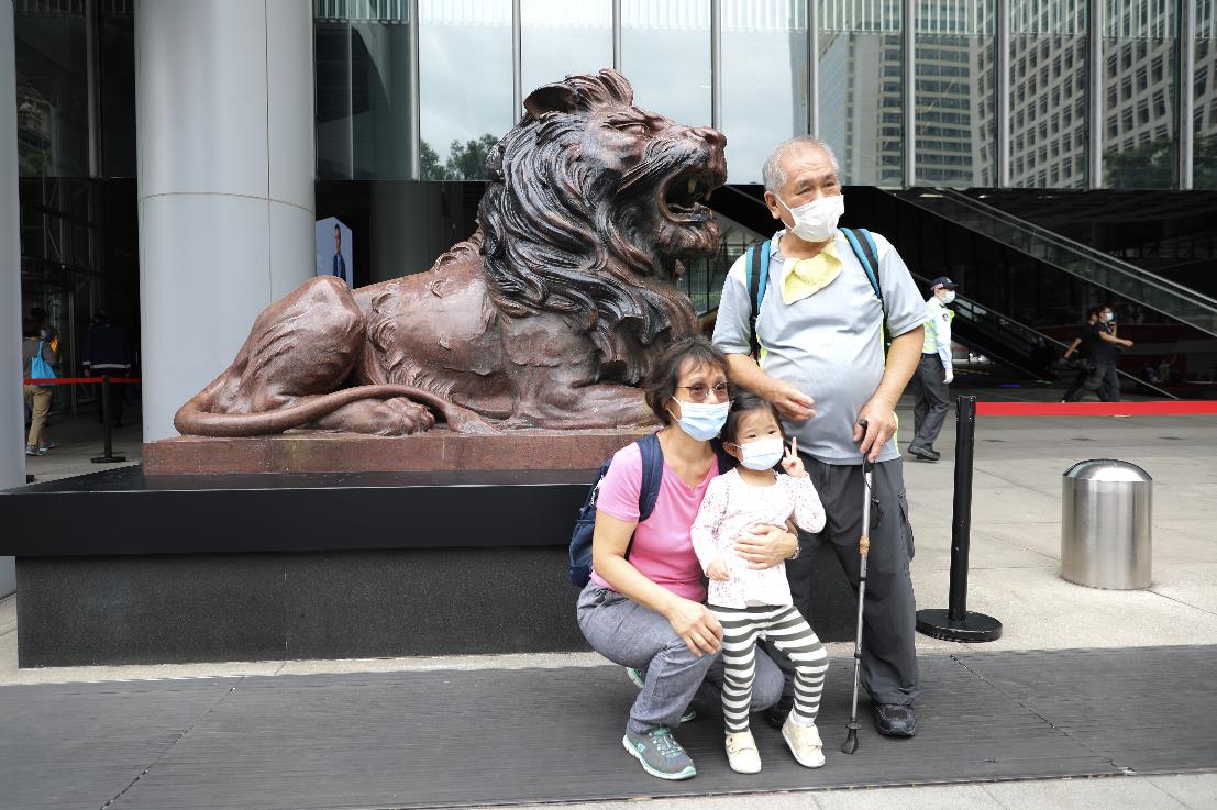 10月22日上午，滙豐銅獅重開，工作人員為獅子揭布並點睛。一些市民和滙豐員工特地前來合影留念，現場可見銅獅身上上大部分污漬被清理，只留有此前被燒過的痕跡。
市民林先生表示，見到銅獅重開感到高興，形容銅獅子是屬於香港人的集體回憶，他希望滙豐能夠將總部搬回香港，早日重振旗鼓。圖為：市民在銅獅子前影相留念（大公文匯全媒體記者 李斯哲 攝）
