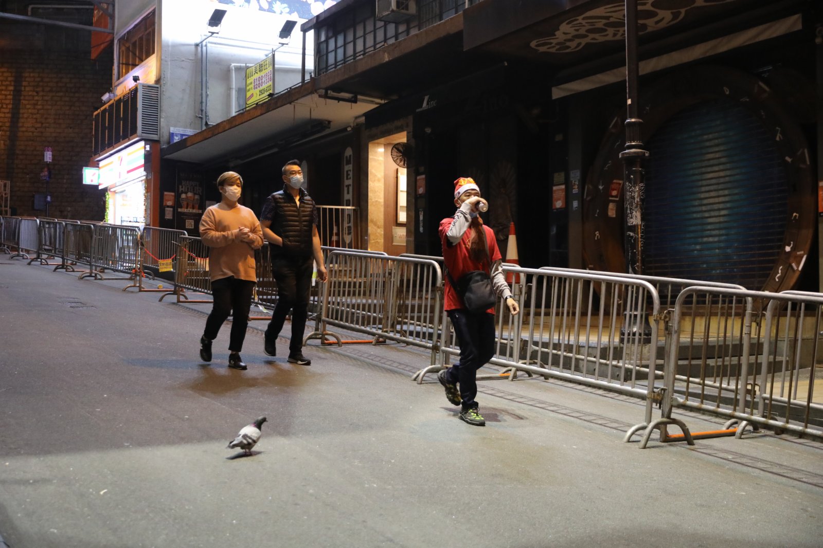 24日，平安夜蘭桂坊街頭「水靜河飛」，酒吧停業，食肆禁堂食，只有少數市民在閒逛。在各個路口均有警察巡邏維持秩序，同時牌照事務署的工作人員到多個商廈巡查，查看有無場所違規營業（大公文匯全媒體記者 李斯哲攝）