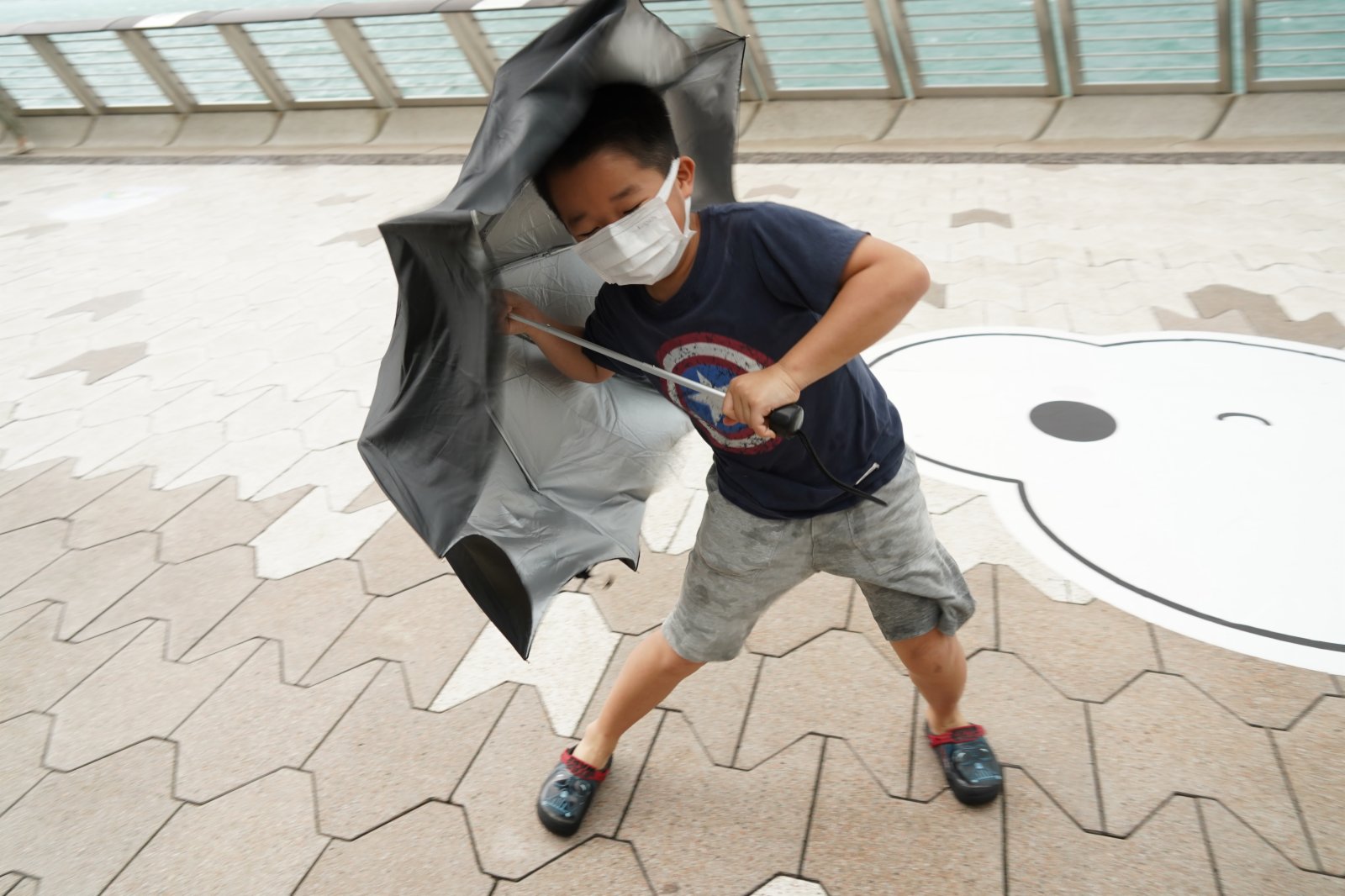 強烈熱帶風暴「圓規」已增強為颱風，天文台昨日（12日）下午5時20分發出八號東北烈風或暴風信號，目前仍然生效。圖為今日（13日）八號風球下，頂風出行的市民。（記者林良堅 攝）