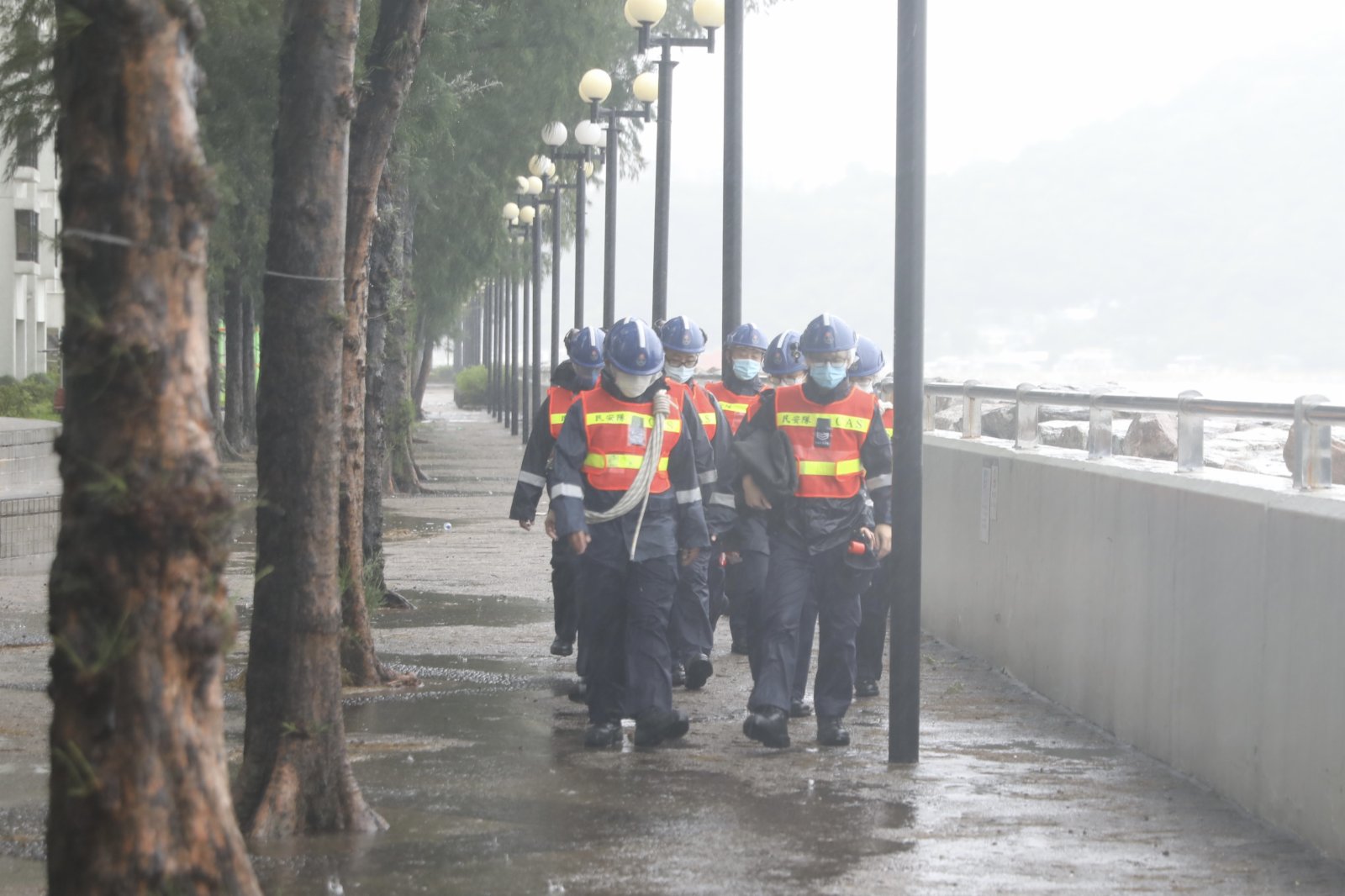 在杏花邨，橫風橫雨，海浪不時拍打岸邊，少許海水湧上海濱長廊，更有人專程到場追風。民安隊則在岸邊不時巡邏保障安全，也有工人冒着暴雨清理屋苑內昨晚海水倒灌的泥沙。（記者李斯哲 攝）