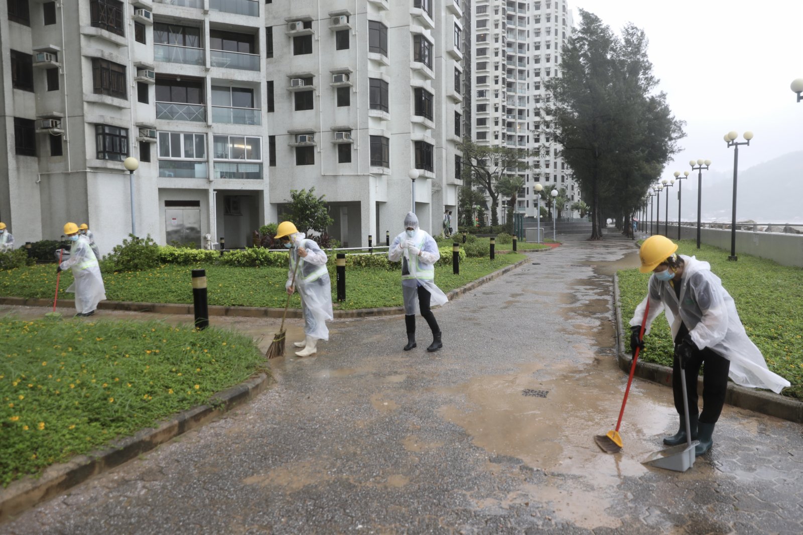 在杏花邨，橫風橫雨，海浪不時拍打岸邊，少許海水湧上海濱長廊，更有人專程到場追風。民安隊則在岸邊不時巡邏保障安全，也有工人冒着暴雨清理屋苑內昨晚海水倒灌的泥沙。（記者李斯哲 攝）