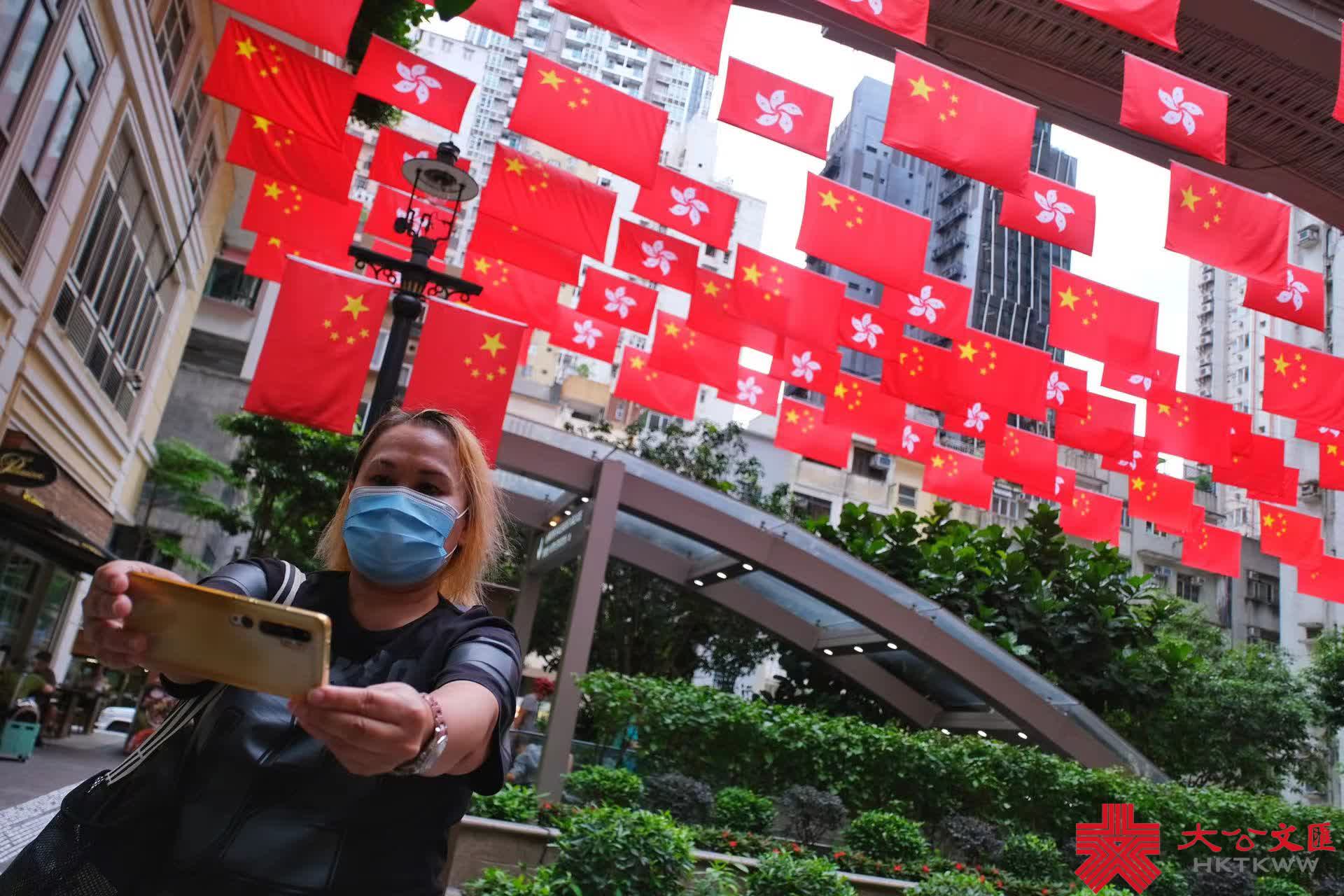 今年是香港回歸祖國25周年，為慶祝這一盛事，街頭處處洋溢節日氣氛。灣仔利東街中庭掛起百多面中華人民共和國國旗和香港特別行政區區旗，形成一片壯闊「旗海」，街邊燈柱亦懸掛國旗，引得不少途人影相打卡，感受喜迎回歸25周年的喜慶氛圍。（大公文匯全媒體記者麥鈞傑攝）