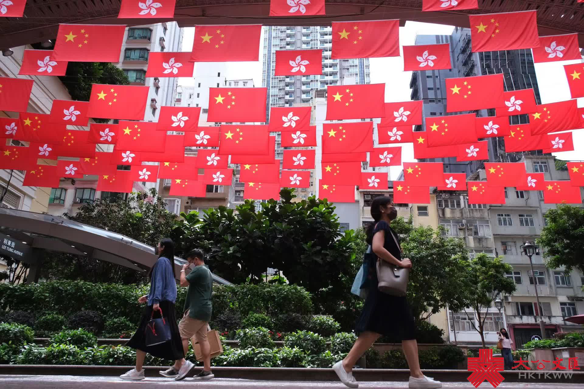 今年是香港回歸祖國25周年，為慶祝這一盛事，街頭處處洋溢節日氣氛。灣仔利東街中庭掛起百多面中華人民共和國國旗和香港特別行政區區旗，形成一片壯闊「旗海」，街邊燈柱亦懸掛國旗，引得不少途人影相打卡，感受喜迎回歸25周年的喜慶氛圍。（大公文匯全媒體記者麥鈞傑攝）