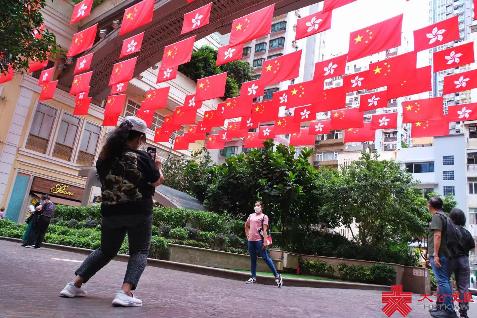 今年是香港回歸祖國25周年，為慶祝這一盛事，街頭處處洋溢節日氣氛。灣仔利東街中庭掛起百多面中華人民共和國國旗和香港特別行政區區旗，形成一片壯闊「旗海」，街邊燈柱亦懸掛國旗，引得不少途人影相打卡，感受喜迎回歸25周年的喜慶氛圍。（大公文匯全媒體記者麥鈞傑攝）