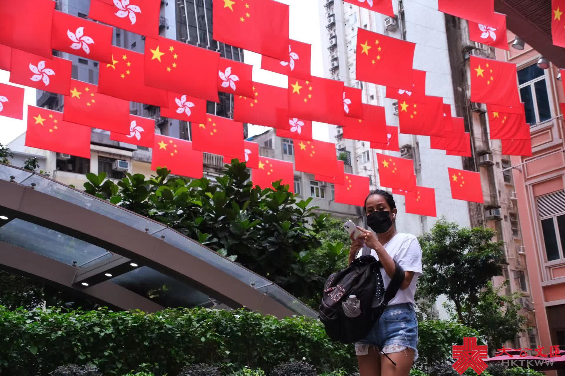 今年是香港回歸祖國25周年，為慶祝這一盛事，街頭處處洋溢節日氣氛。灣仔利東街中庭掛起百多面中華人民共和國國旗和香港特別行政區區旗，形成一片壯闊「旗海」，街邊燈柱亦懸掛國旗，引得不少途人影相打卡，感受喜迎回歸25周年的喜慶氛圍。（大公文匯全媒體記者麥鈞傑攝）