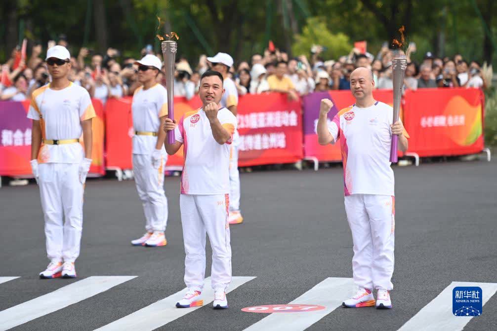 9月14日，火炬手楊文傑（左）、黃軍民在火炬傳遞中。

當日，杭州亞運會火炬在浙江省台州傳遞。（新華社記者黃宗治攝）