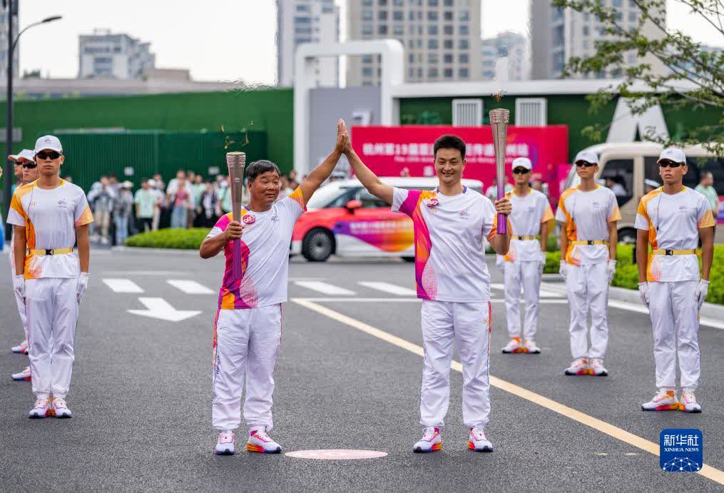 9月14日，火炬手郭文標（左）和呂義聰在火炬傳遞中。

當日，杭州亞運會火炬在浙江省台州傳遞。（新華社記者孫非攝）