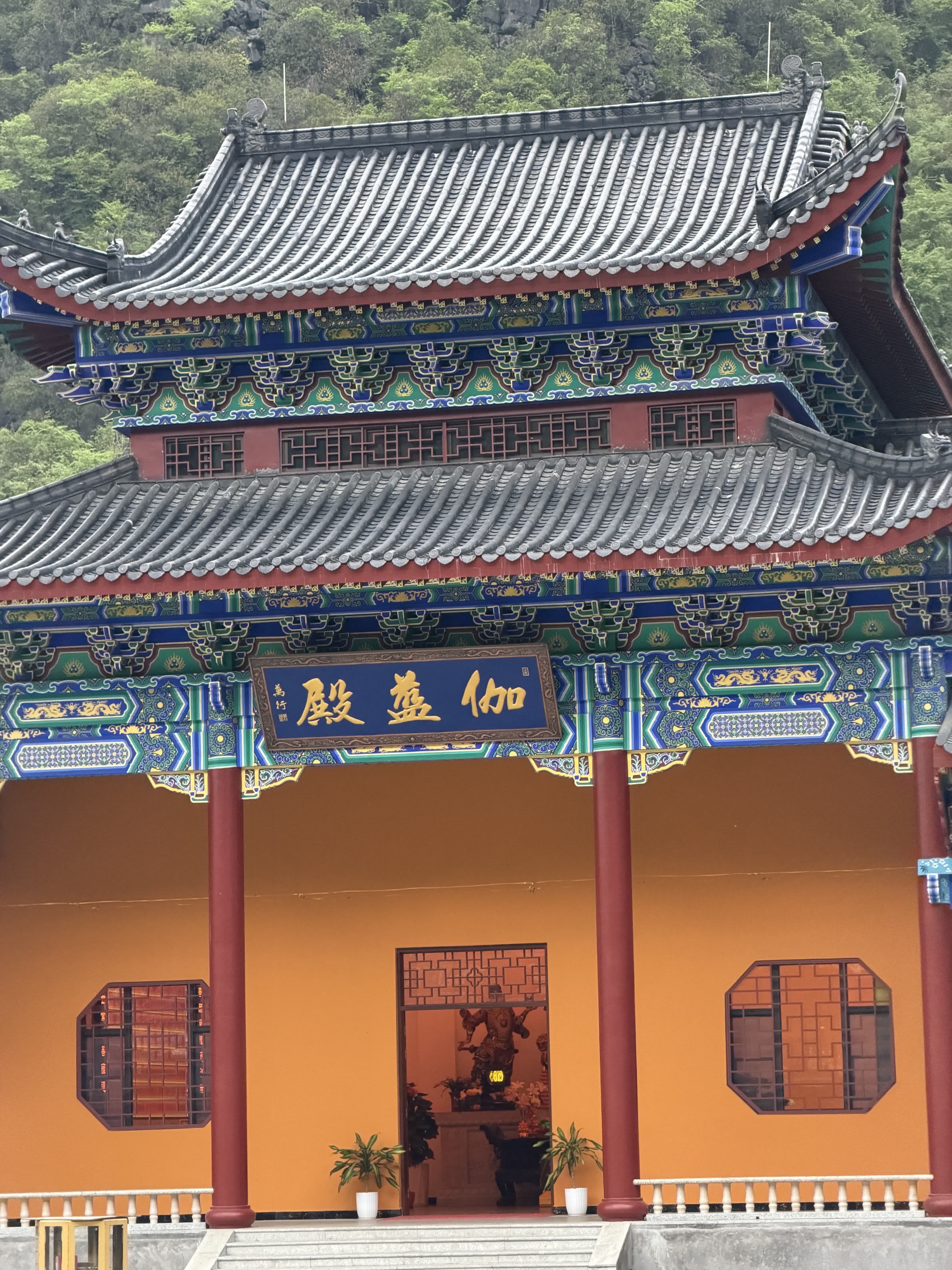 夏日，東華禪寺綠樹蔥蘢，青山環抱之中，藏着治癒人心的靜謐禪境。明黃院牆搭配朱紅樑柱，飛檐斗拱彩繪精巧，韻味十足。三門殿、伽藍殿錯落有致，牌匾古樸莊重，土地廟紅燈點綴，煙火與禪意相融。
閒走寺院，伴着淡淡香火，浮躁慢慢沉澱。尋半日閒暇走入此間，賞中式建築之美，靜心放空，在草木梵音裏收穫安然鬆弛。