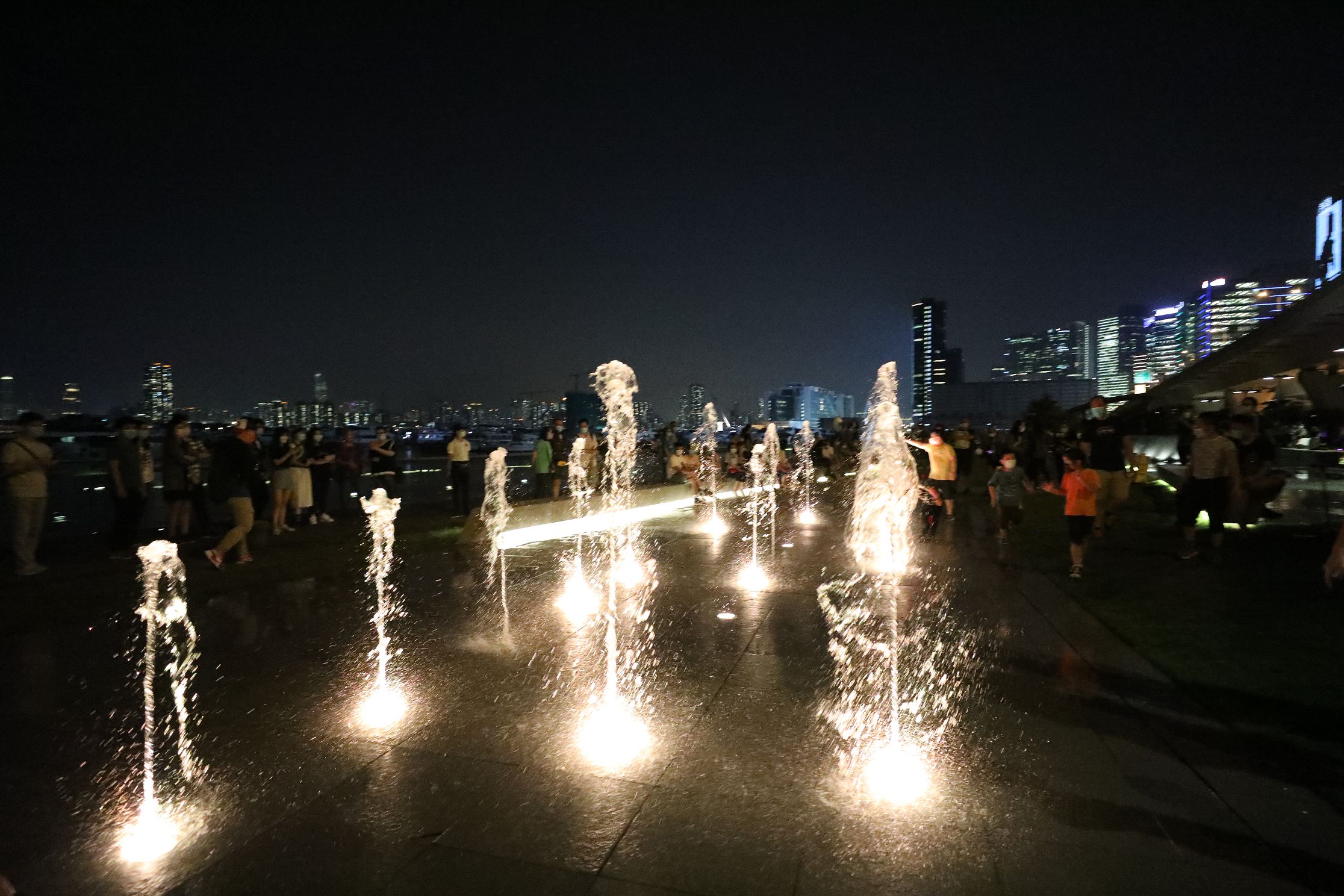 入夜後，音樂噴泉在燈光的配合下更顯閃亮璀璨，吸引不少市民駐足。（香港文匯報記者 萬靈霜 攝）