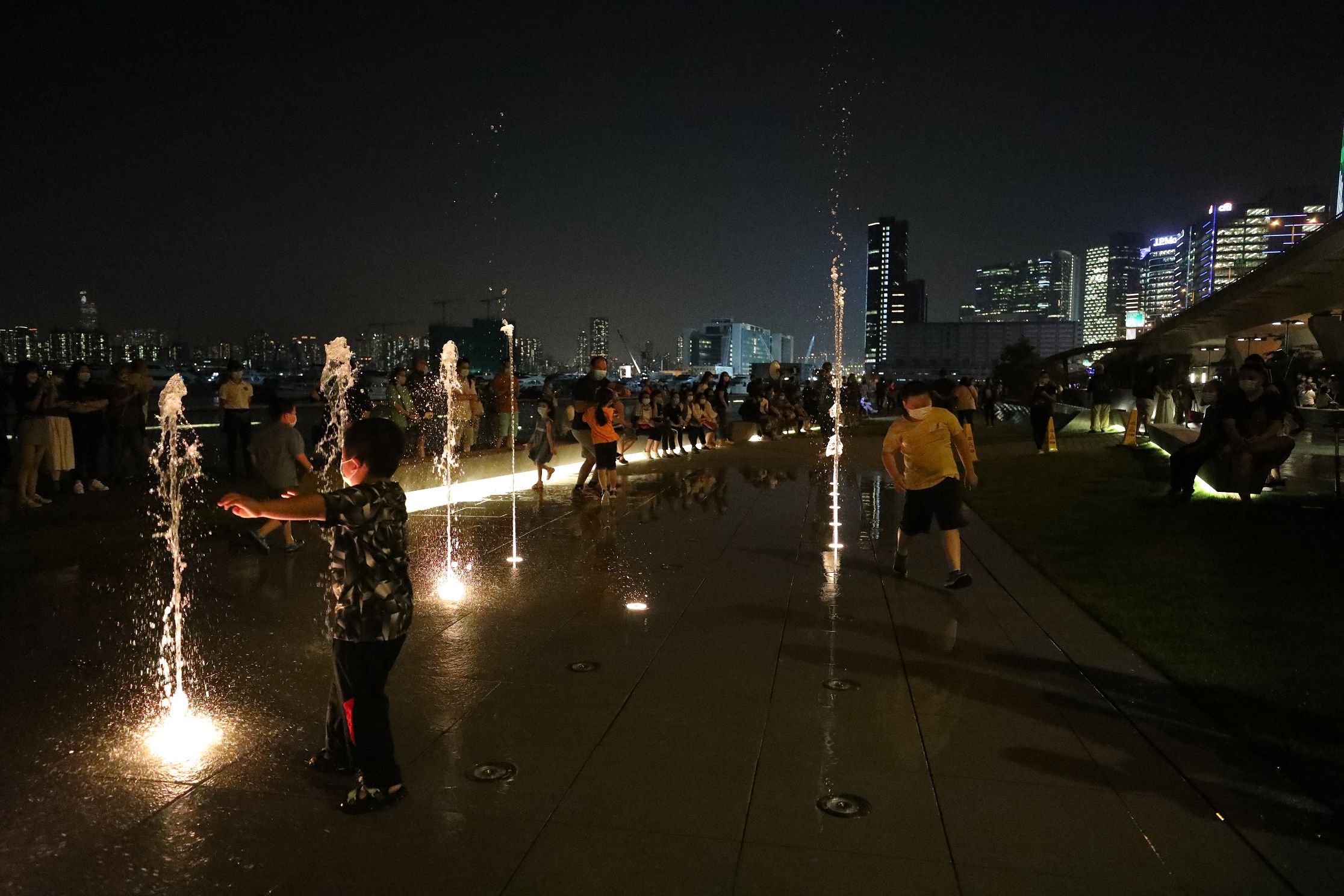 許多小童興奮與噴泉互動，穿梭水柱間嬉戲。（香港文匯報記者 萬靈霜 攝）