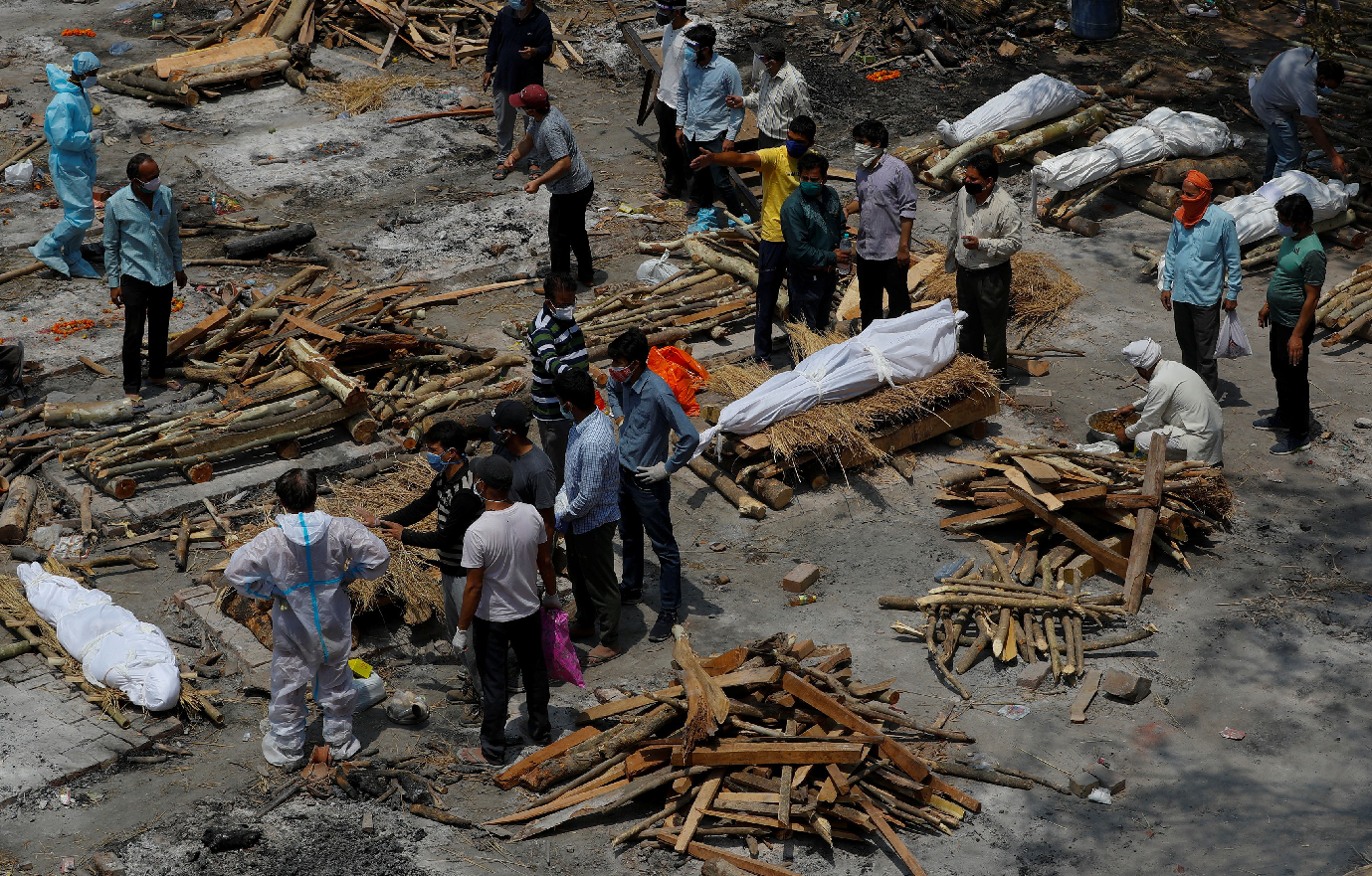 印度疫情瀕臨失控，今日（27日）新增32.3萬宗新冠病毒確診，已經連續6日單日確診超過30萬，累計確診個案增至1764萬，另外新增2771人死亡，累計死亡人數超過19.7萬。由於醫療及殯葬場所匱乏，大批確診死亡者的屍體來不及處理，親人只能忍痛在露天場所生火焚燒火化。（圖：路透社）