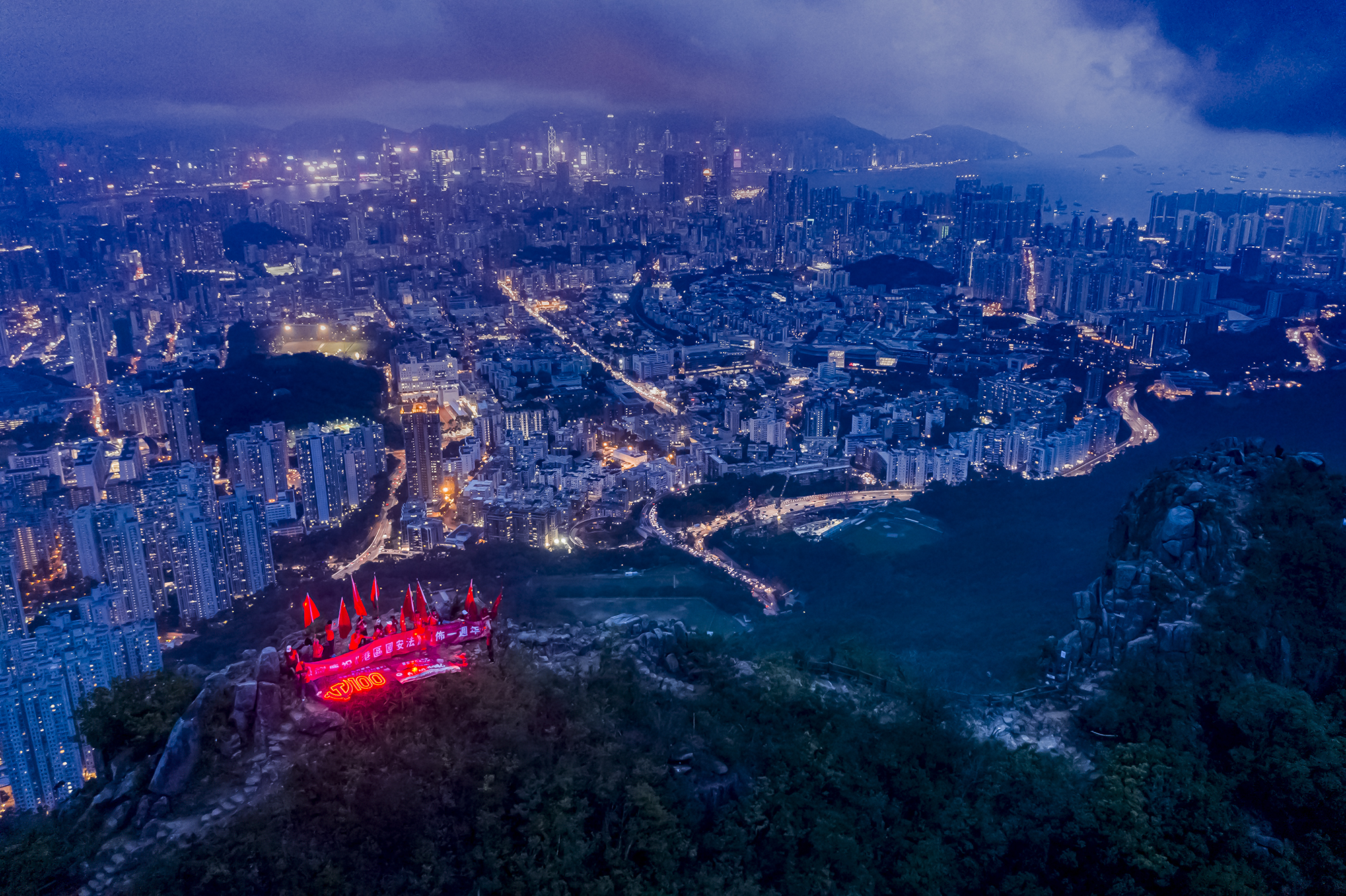 團体點亮中國共產黨黨徽形象的燈光與「100」的字樣，高舉五星紅旗，熱烈慶祝黨的生日及香港回歸24周年。（受訪者供圖）