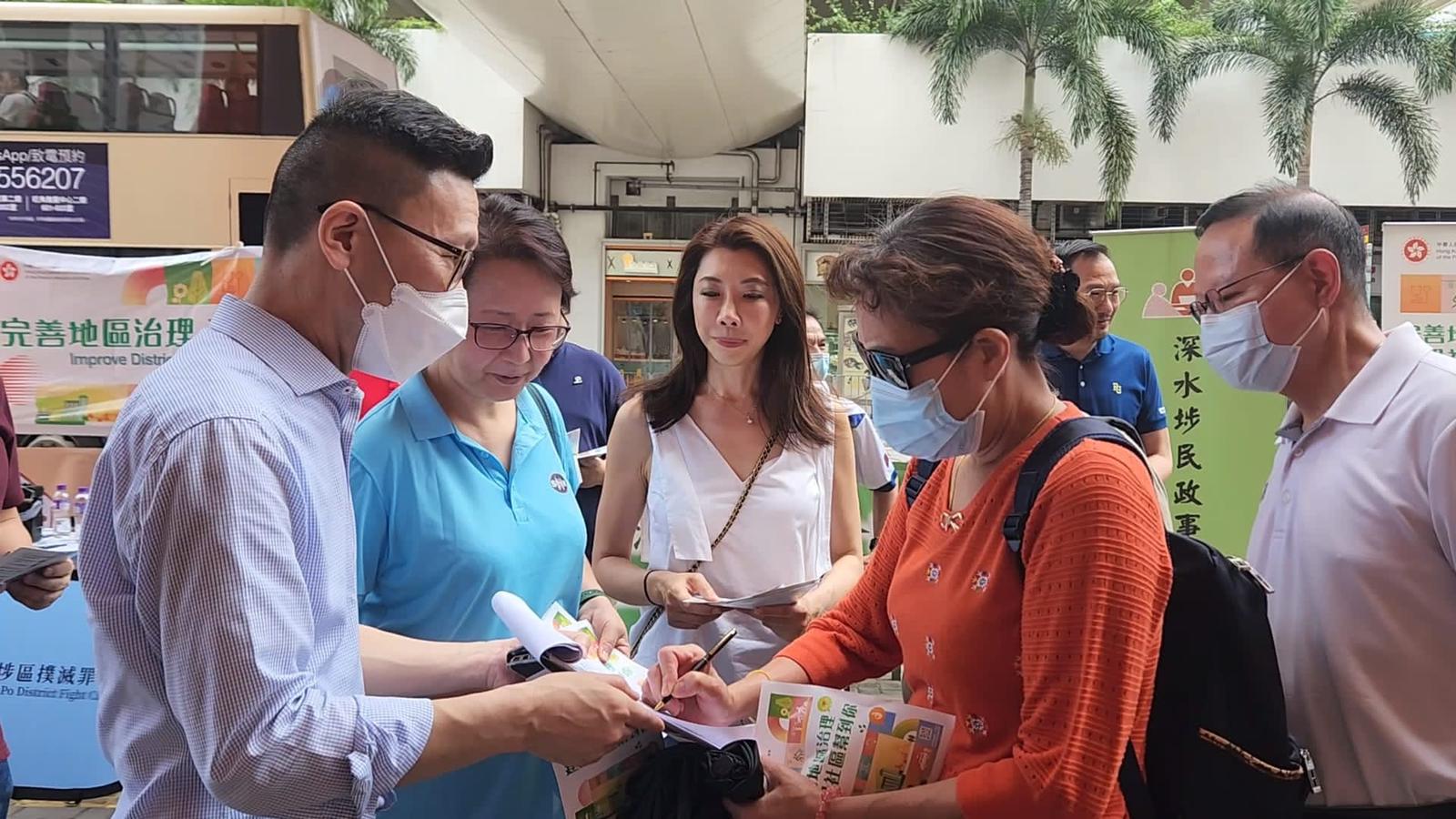 石硤尾地鐵站出口，深水埗民政事務專員黃昕然(左)正收集市民的簽名。(受訪者提供)