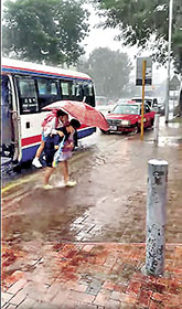 ■暖心校工阿姨孭學生行過積水。 網上圖片