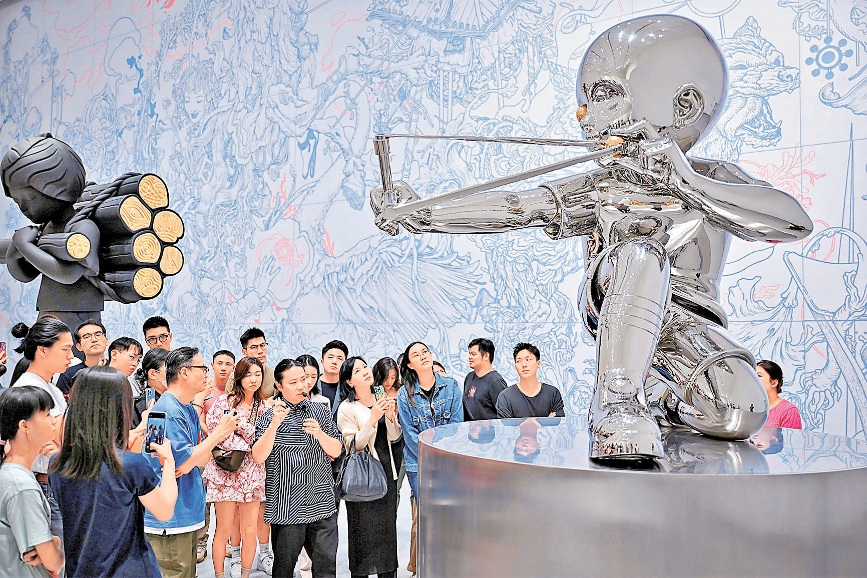 ■簡明向參觀者介紹其鏡面不銹鋼作品《彈弓》。