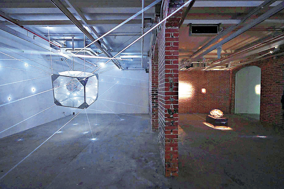 ■鄭靖的裝置作品《時空際會》，以懸浮的立方體為核心，向外投射的光束從不同方位穿透油街倉庫的空間。