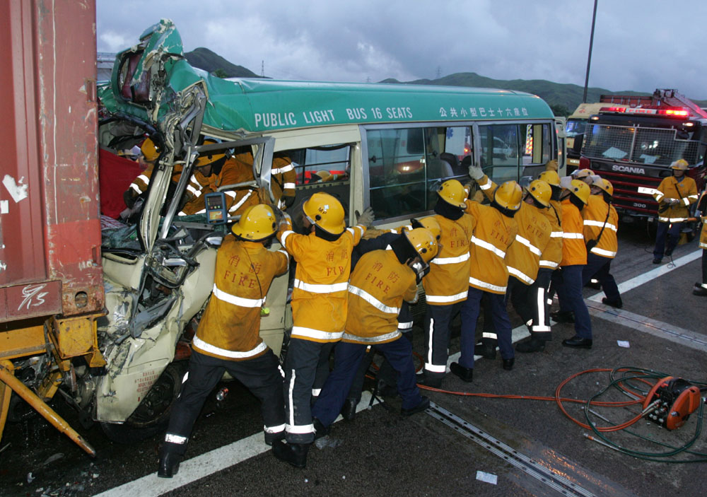 　　圖：意外發生後消防員全力救人，小巴連司機17人死傷（本報攝）