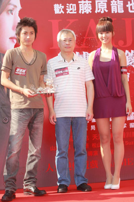 　　圖：Maggie（右）不介意擔任歡樂小姐遞紀念品給藤原龍也（左）