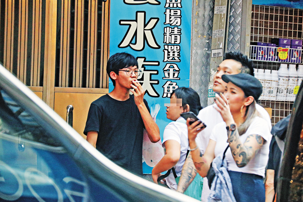 　　圖：4月26日下午，鍾翰林帶着身穿校服的女友在金魚街，煙癮一起，馬上在街上煲煙