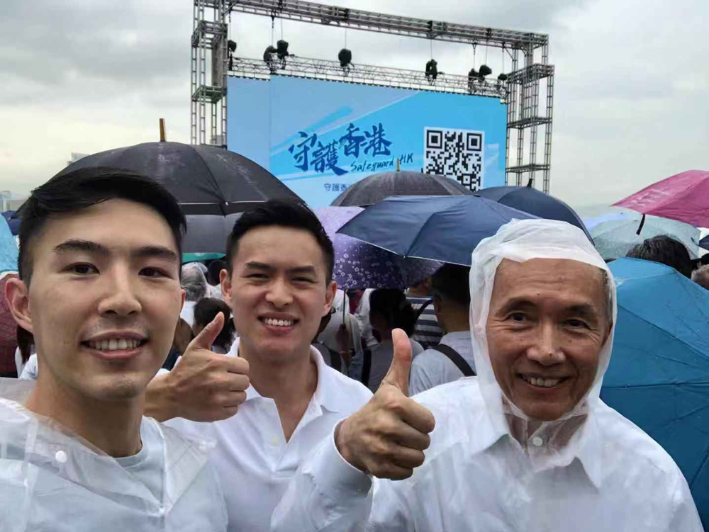 　　圖：信和集團主席黃志祥（右）與兒子黃永耀（中）及黃永龍（左）冒雨出席7．20撐警大會