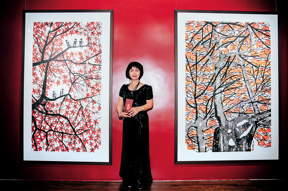 　　圖：策展人張朱宇，其旁作品為周天黎的《勢催春暖百花開》（左）和《秋實》\主辦方供圖