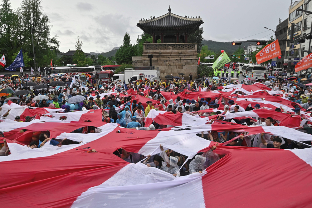 　　圖：韓國民眾8月15日剪碎一幅巨大的旭日旗\法新社