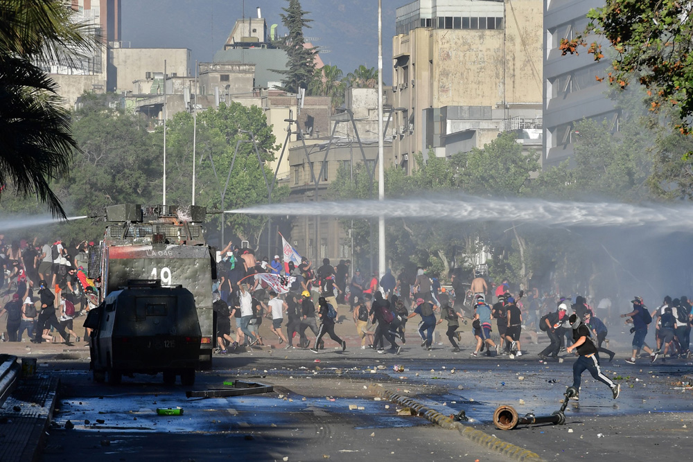 　　圖：智利示威者6日在聖地亞哥與警方發生衝突，警方出動水炮車驅散人群 法新社
