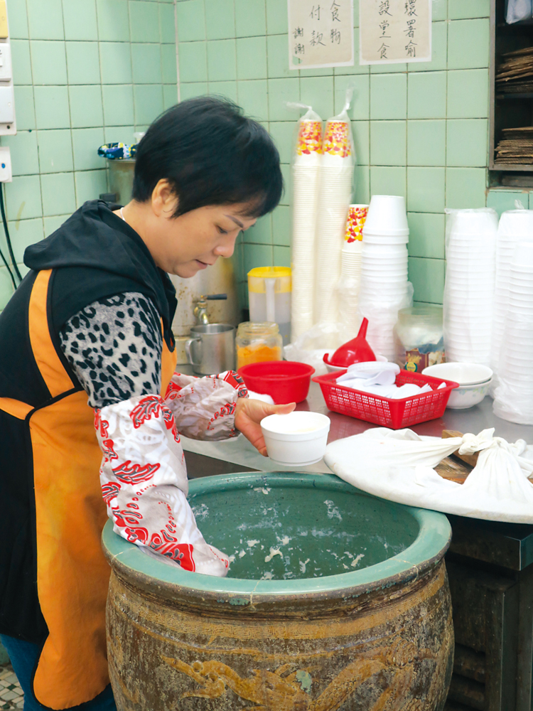 　　圖：店員從瓦缸扌畢豆腐花奉客