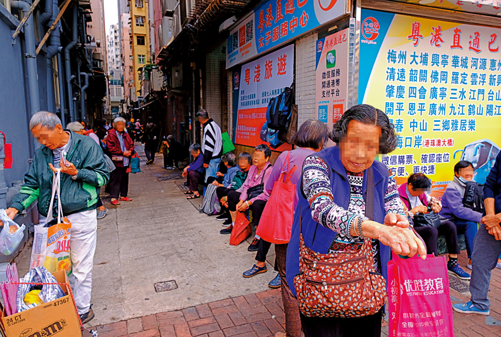 　　圖：輪候功德飯的長者，排隊長龍由店前延伸至後巷