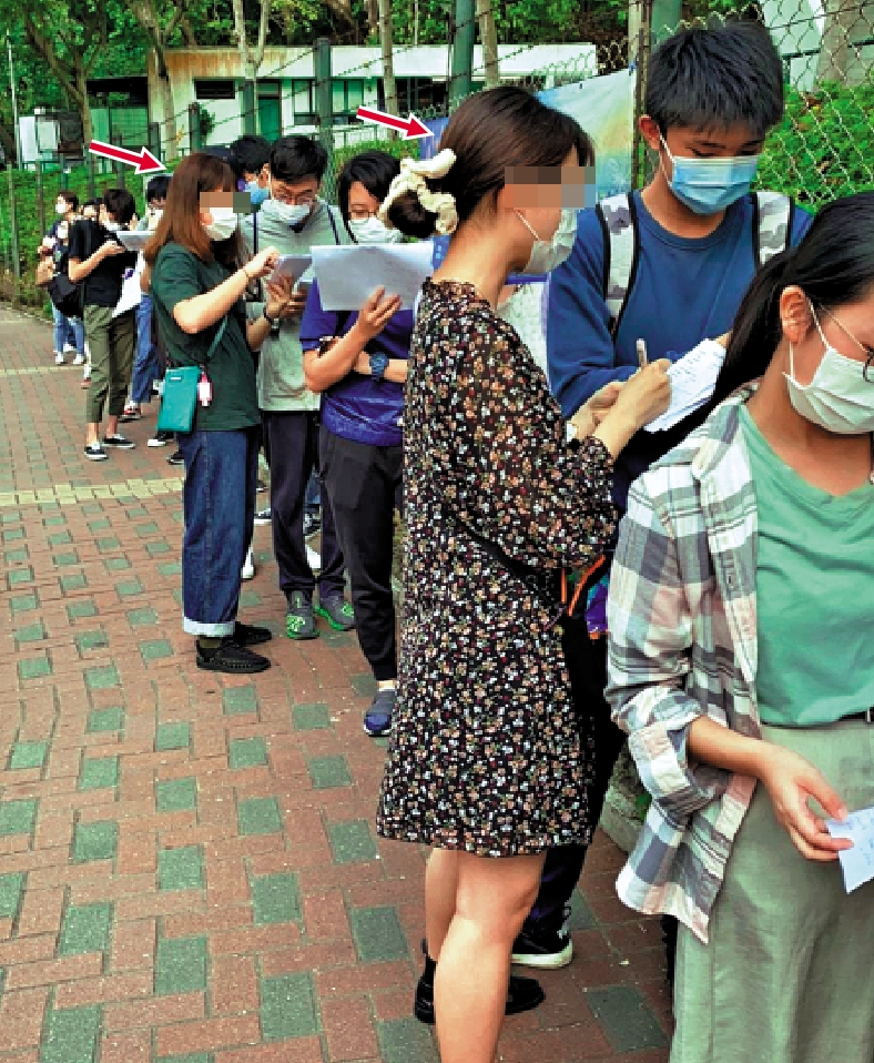 　　圖：兩名神秘女子（箭嘴示）在DSE考場外向等候進場應考的考生填寫問卷，懷疑用作傳銷用途