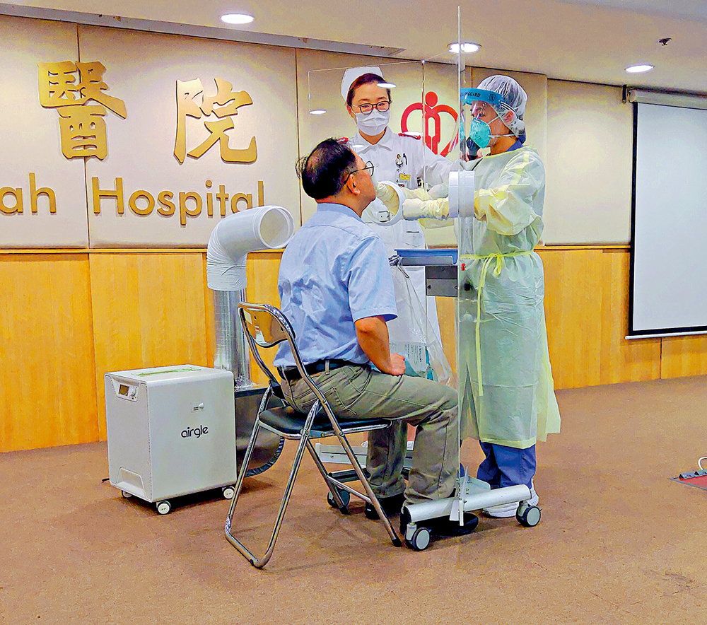 　　圖：「鼻咽屏風」約六呎高，主體由一塊透明膠板製成，上面開有兩個洞口，供醫護人員伸手替病人取樣