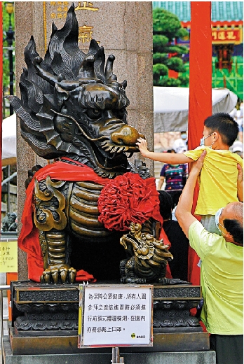 　　圖：有善信抱起小朋友撫摸門口的銅麒麟，也有善信擔心不衞生「眼看手勿動」，現場亦有廣播提醒市民勤洗手\中通社