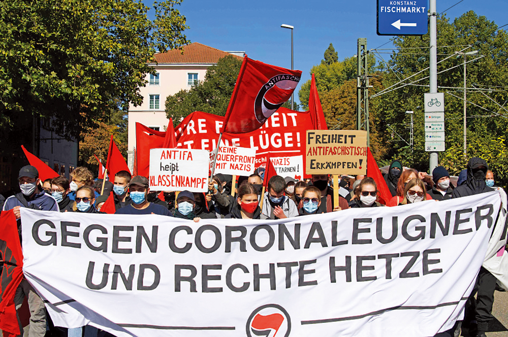 　　圖：德國南部城市康斯坦茨，民眾4日舉着寫有「反對新冠否定者和右翼暴徒」的橫幅支持防疫\法新社