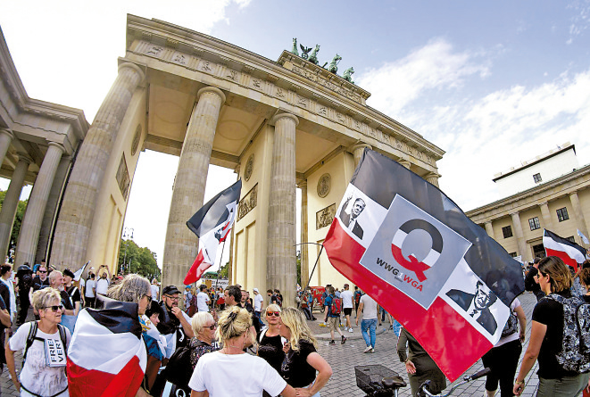 　　圖：「Q粉」舉着特朗普旗幟在德國柏林勃蘭登堡門前參加集會\美聯社