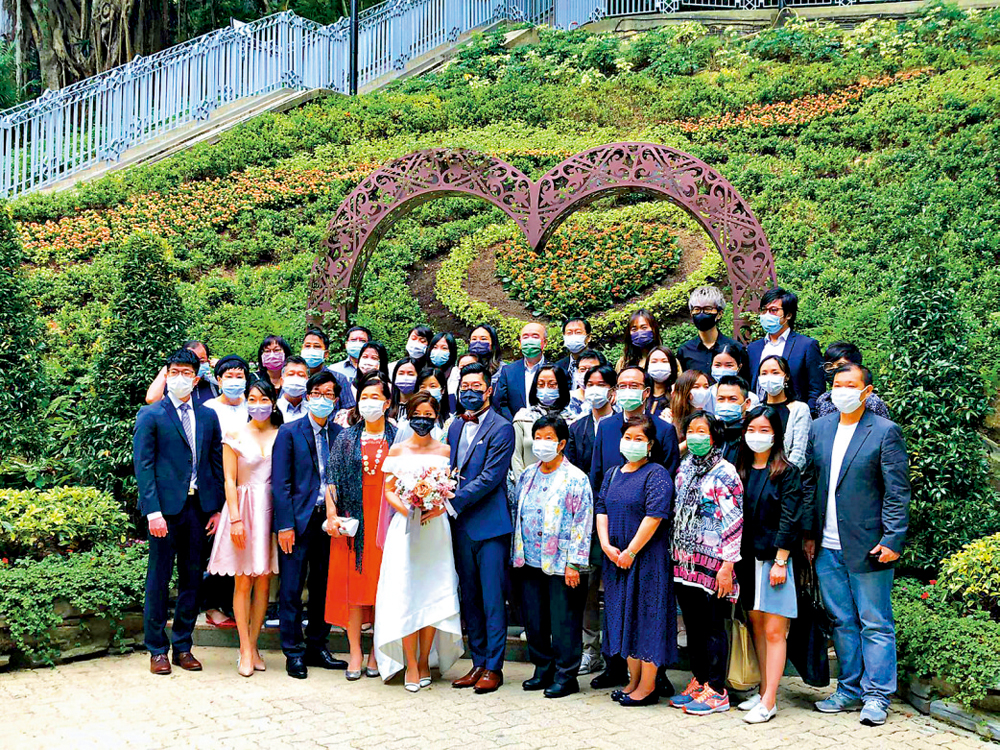 　　圖：婚禮限聚人數昨日放寬至50人，在紅棉路婚姻登記處註冊，新人與到賀親友在心形拱橋合影留念\大公報記者解雪薇攝