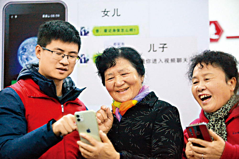 　　圖：11月26日，揚州市文匯街道春江社區的志願者在教老年人使用智慧手機\新華社