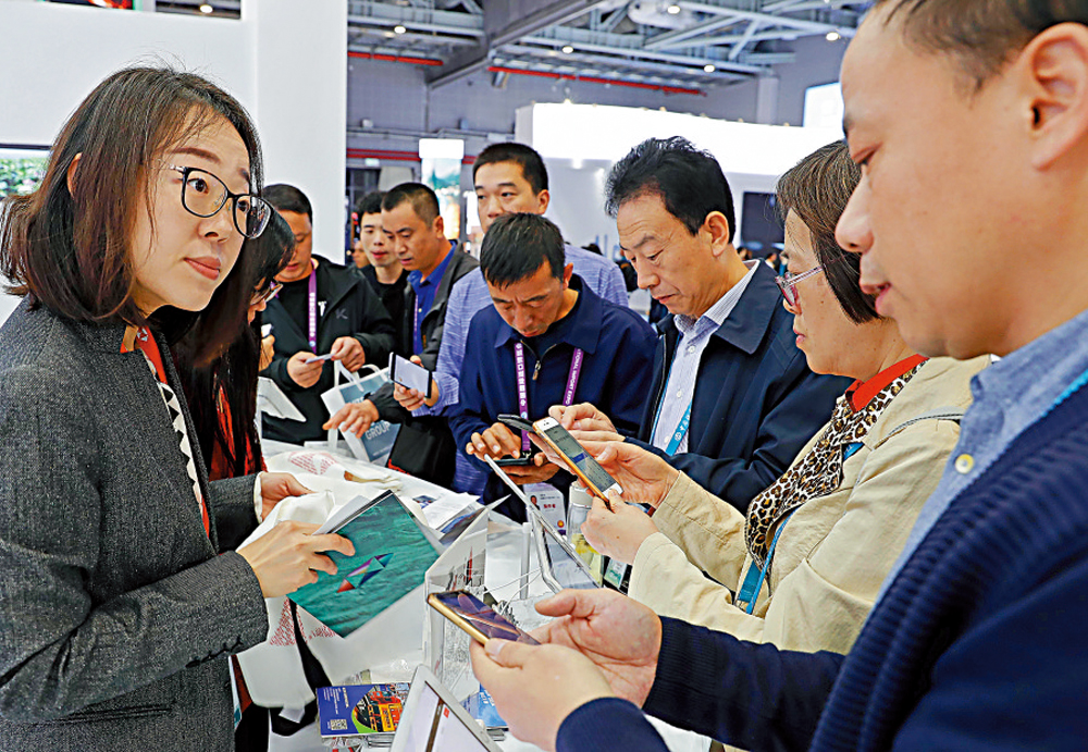 　　圖：在第二屆進博會上，參觀者與來自香港的滙豐銀行員工交流\資料圖片