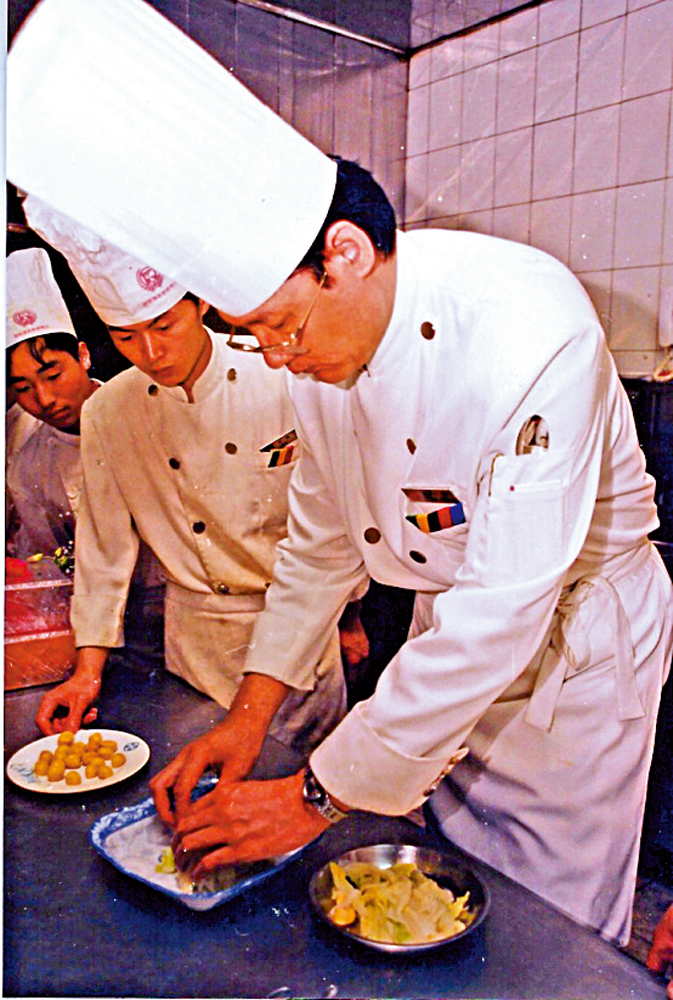 　　圖：1980年代，大董（右）在團結湖烤鴨店向徒弟示範擺盤。