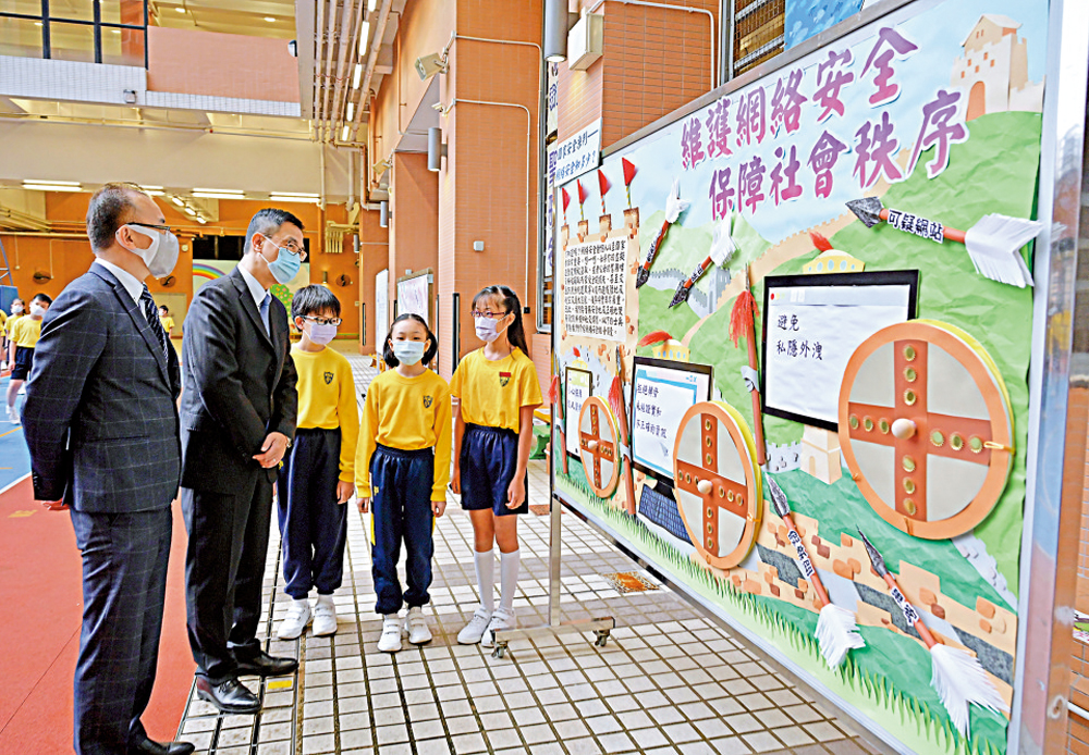 　　圖：楊潤雄（左二）到訪聖公會聖雅各小學，觀賞國家安全校園壁報設計比賽的學生作品。\中通社