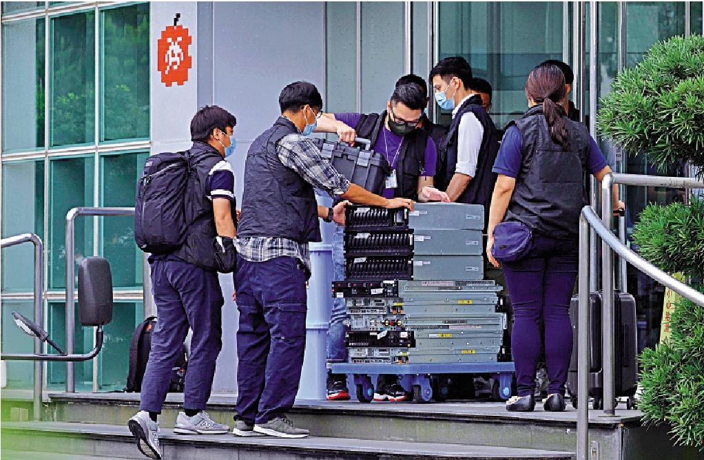 　　圖：警員在《蘋果日報》辦公地點檢走大批電腦設備，用作搜證之用。\法新社