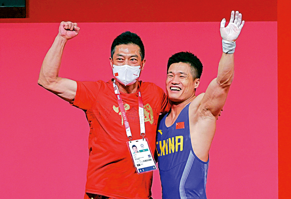 　　圖：呂小軍（右）曾為養家放棄舉重。\新華社