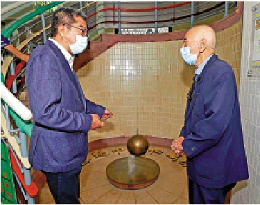 　　圖：羅富國校友會前會長馮源（右）向發展局局長黃偉綸（左）介紹般咸道官立小學其中一個歷史印記「傅科擺」。