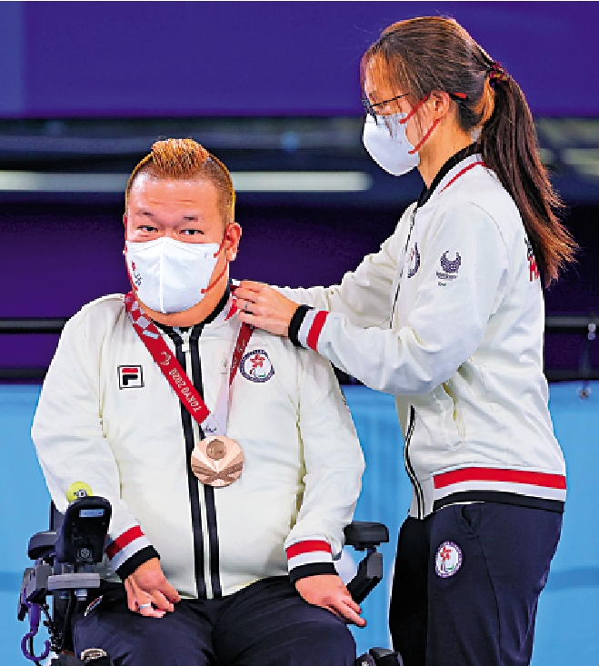 　　圖：梁太施珊珊（右）為梁育榮掛上銅牌。\路透社