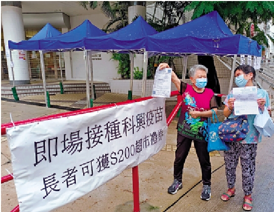 　　圖：外展隊昨起一連三日在葵涌石籬社區會堂，為區內長者提供一站式接種服務。圖為打針後長者興奮展示針卡。