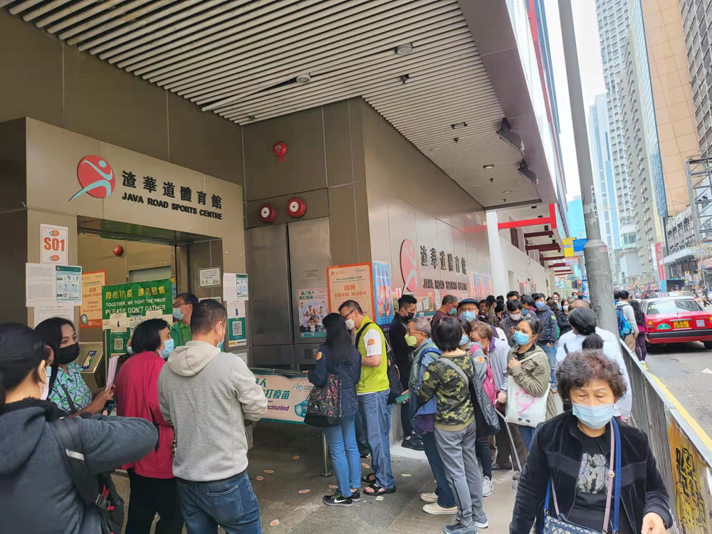 　　圖：渣華道體育館接種中心外打蛇餅，眾多市民排隊等候打疫苗。\大公報記者馮嘉諾攝