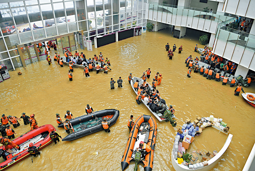 　　圖：二○二一年七月二十二日，在鄭州市阜外華中心血管病醫院門診部，救援人員在積水的大廳內駕駛舟艇轉移病患。\新華社