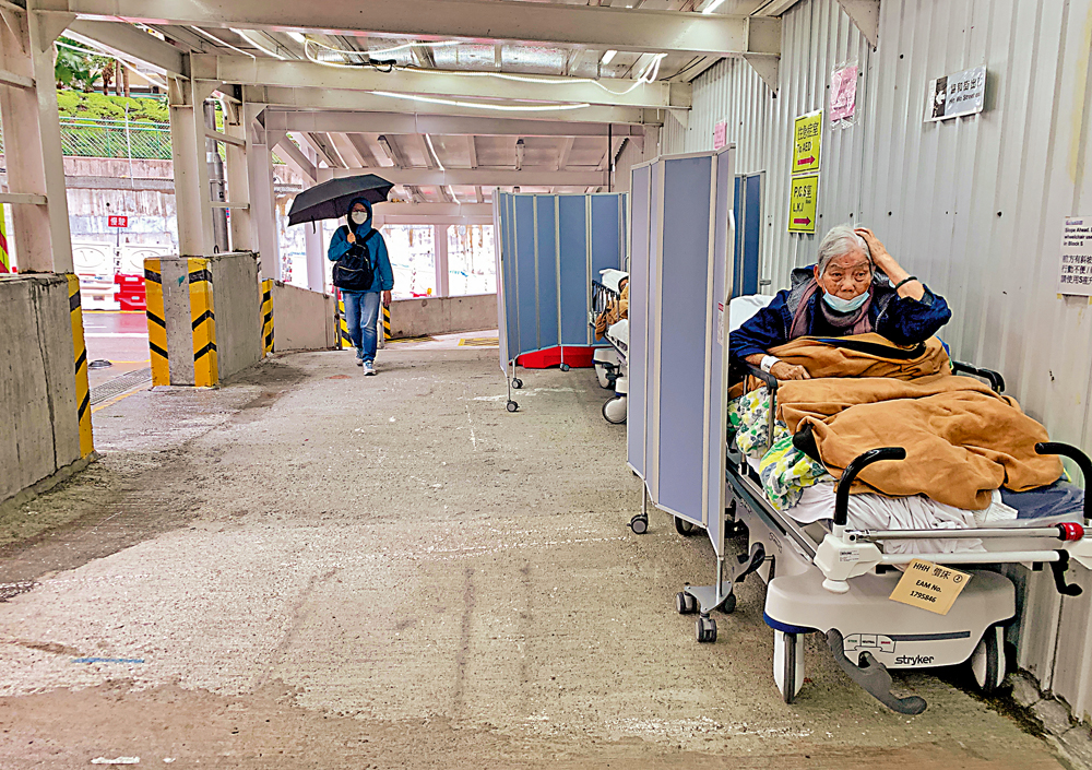 　　圖：聯合醫院外有市民在行人路上等入院，患者被放置在行人路等候入院，途人經過有染疫風險。\大公報記者麥潤田攝