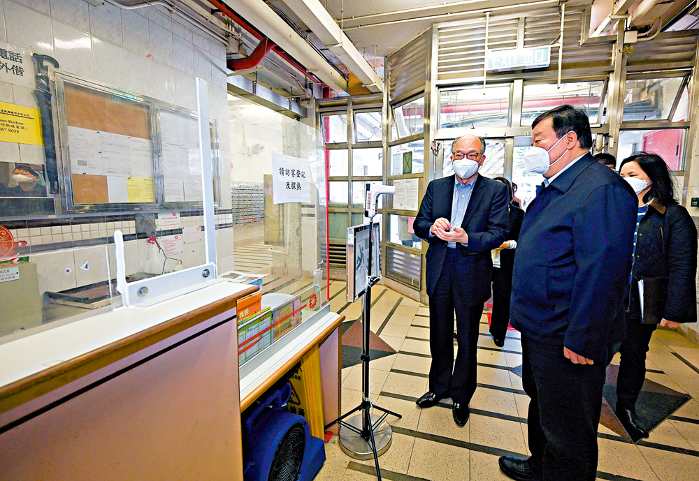 　　圖：梁萬年（中）昨日視察需要圍封強檢的順天邨。運房局局長陳帆（左）在旁講解公屋加強抗疫工作情況。