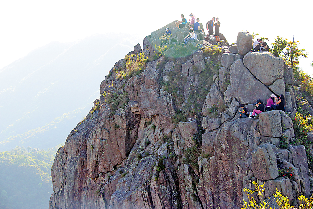　　圖：登山客不顧危險，登上獅子山的岩頂打卡看風景。